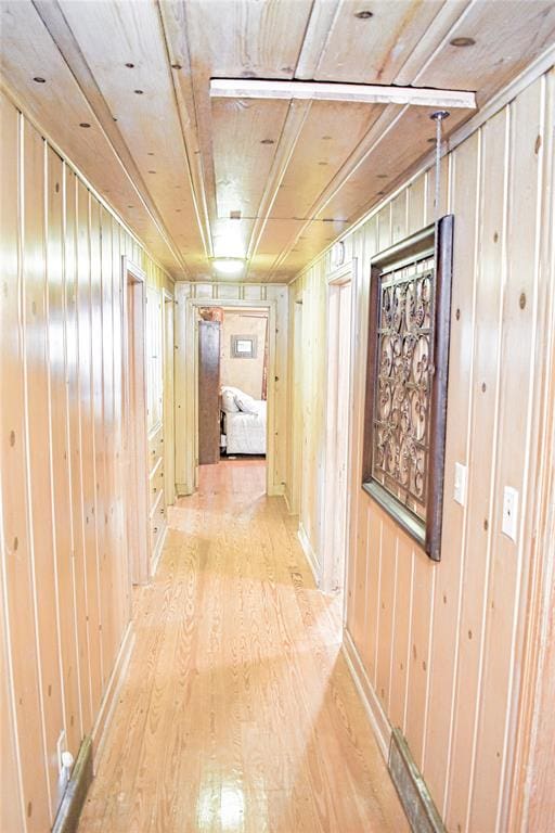 hallway with wood walls and light hardwood / wood-style flooring