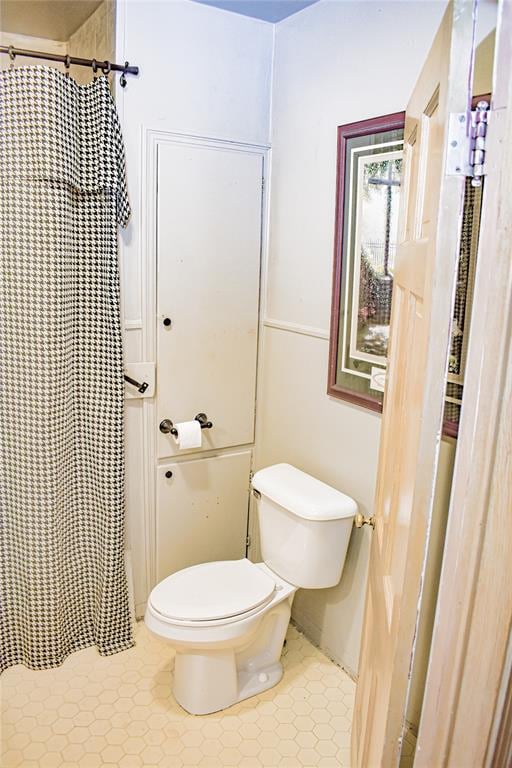 bathroom with a shower with shower curtain and toilet