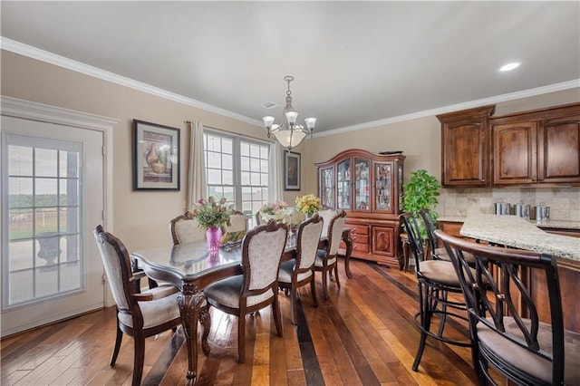 dining area featuring ornamental molding, a healthy amount of sunlight, dark hardwood / wood-style floors, and an inviting chandelier