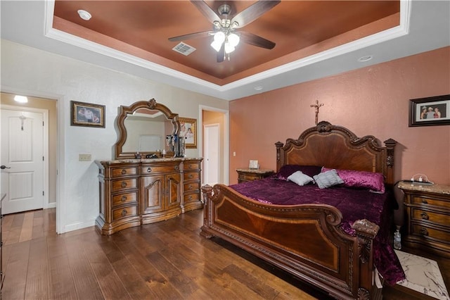 bedroom featuring a tray ceiling, ceiling fan, and dark wood-type flooring