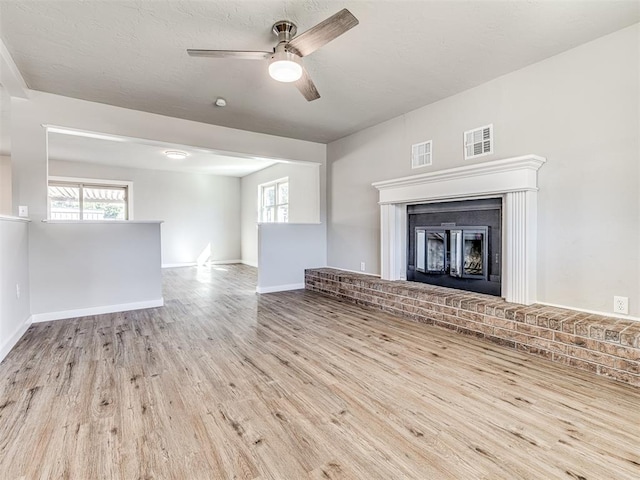 unfurnished living room with light wood-type flooring, a brick fireplace, and ceiling fan