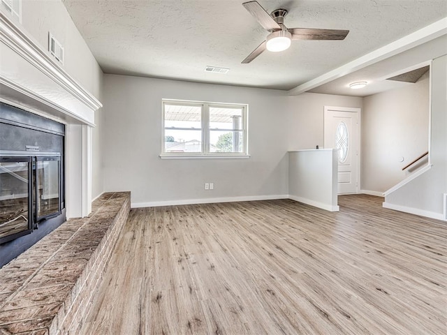 unfurnished living room featuring ceiling fan, light hardwood / wood-style flooring, and a textured ceiling