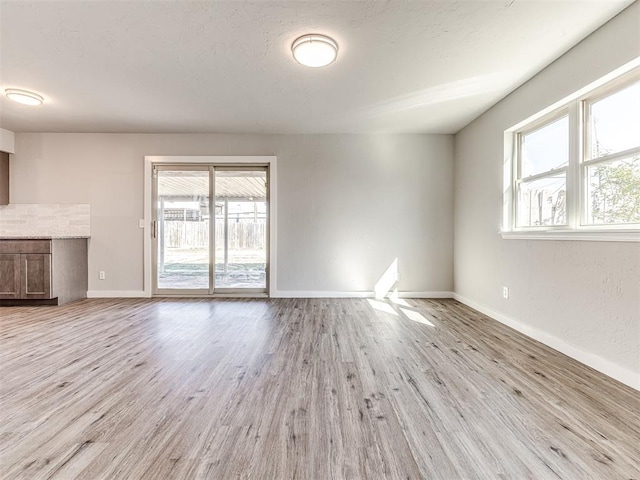 unfurnished living room featuring plenty of natural light and light hardwood / wood-style floors