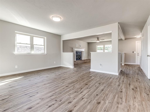 unfurnished living room with plenty of natural light, light hardwood / wood-style floors, a fireplace, and ceiling fan