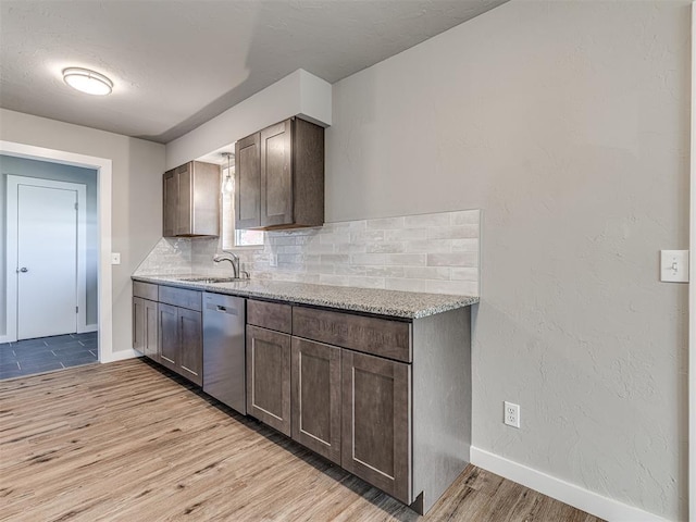 kitchen featuring sink, dishwasher, light stone counters, backsplash, and light wood-type flooring