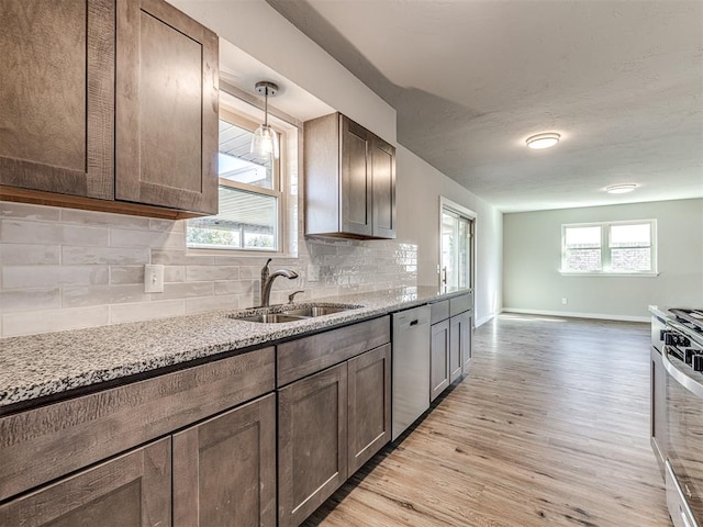 kitchen with sink, stainless steel appliances, light stone counters, light hardwood / wood-style floors, and decorative backsplash