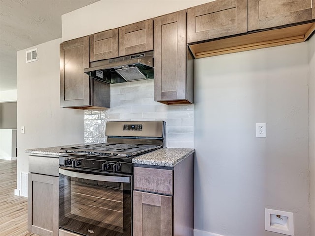 kitchen with light stone countertops, gas stove, light hardwood / wood-style floors, and tasteful backsplash