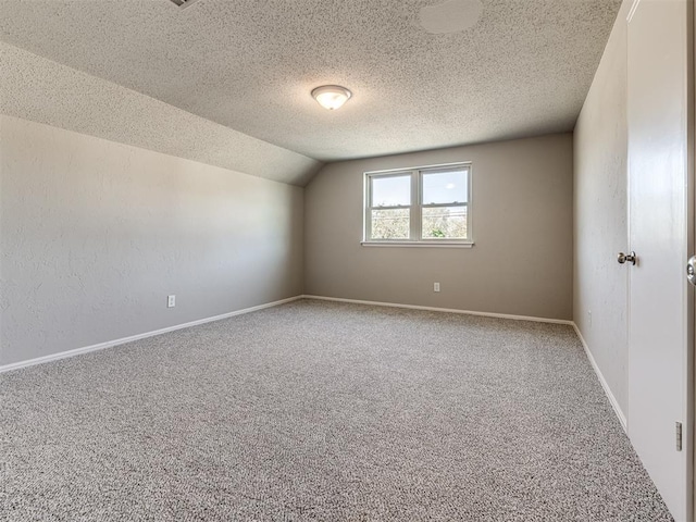 unfurnished room with carpet flooring, a textured ceiling, and vaulted ceiling