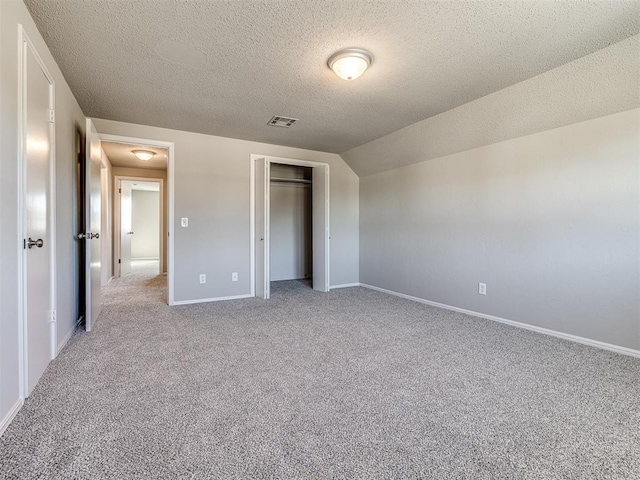 unfurnished bedroom with light colored carpet, lofted ceiling, a textured ceiling, and a closet