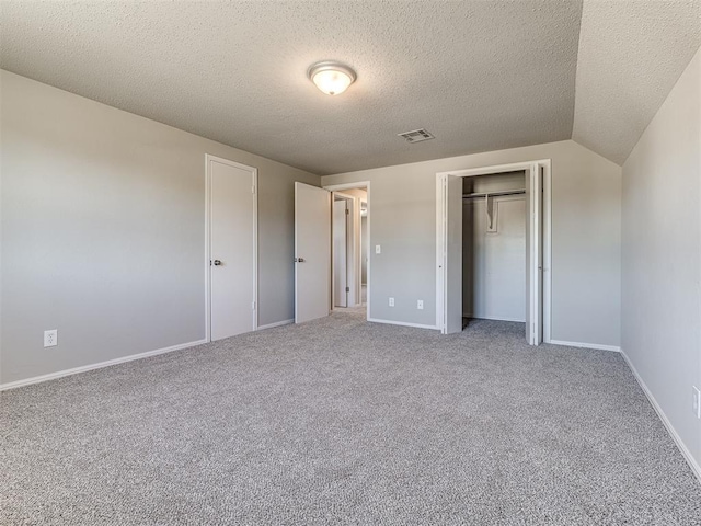 unfurnished bedroom with carpet flooring, lofted ceiling, a closet, and a textured ceiling