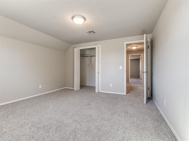 unfurnished bedroom with carpet, a textured ceiling, a closet, and lofted ceiling