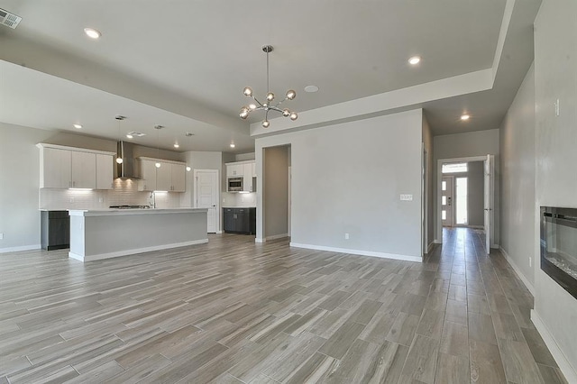 unfurnished living room with light wood-type flooring and an inviting chandelier