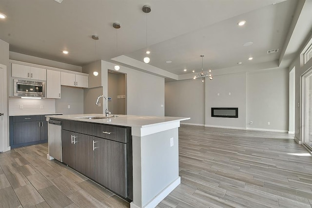 kitchen with pendant lighting, white cabinetry, and a kitchen island with sink