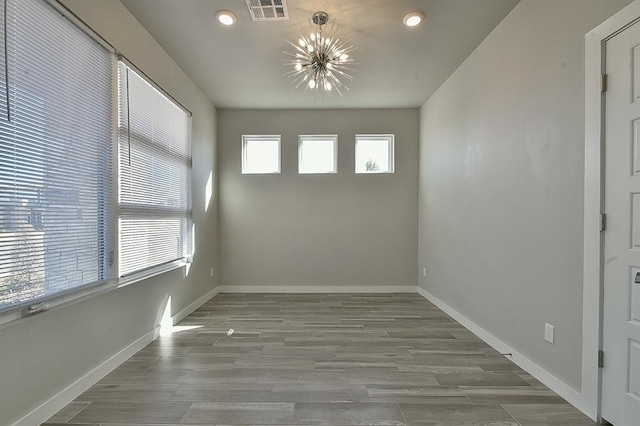 unfurnished room with a chandelier and hardwood / wood-style floors