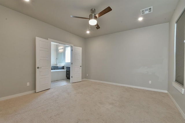 unfurnished bedroom with ceiling fan, light colored carpet, and ensuite bath