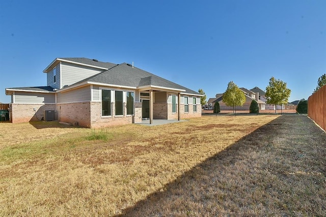 rear view of house featuring a lawn, central air condition unit, and a patio