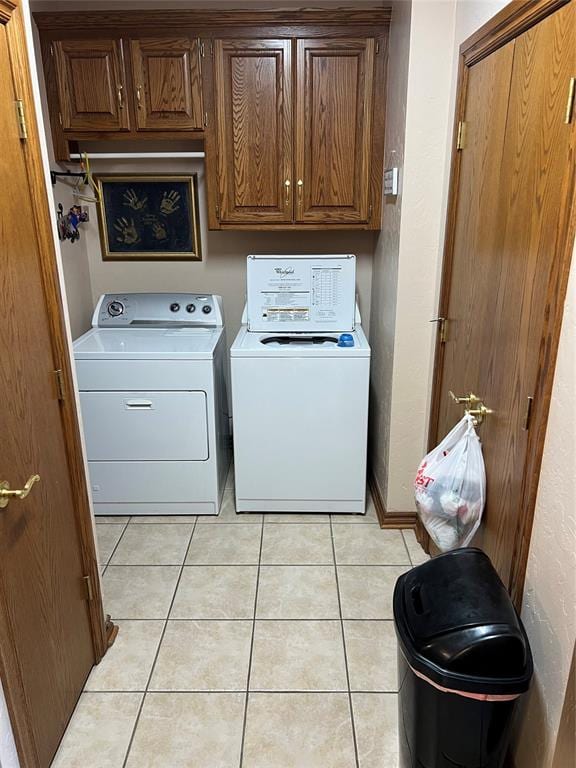 laundry room featuring washer and dryer, light tile patterned floors, and cabinets