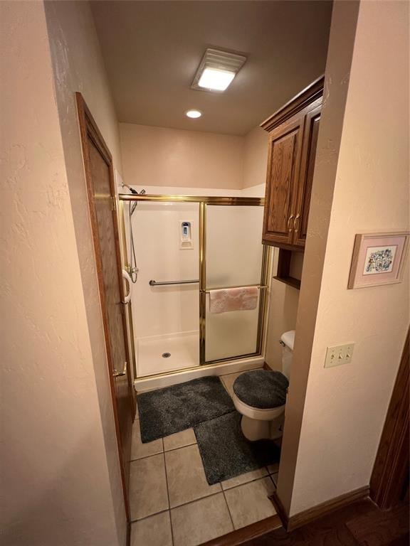 bathroom featuring tile patterned flooring, toilet, and an enclosed shower