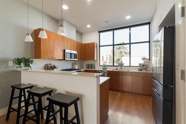 kitchen with kitchen peninsula, appliances with stainless steel finishes, a breakfast bar area, and sink