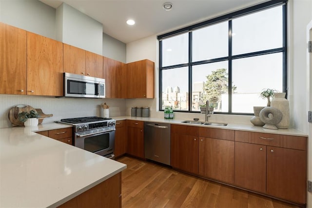 kitchen featuring decorative backsplash, sink, stainless steel appliances, and light hardwood / wood-style flooring