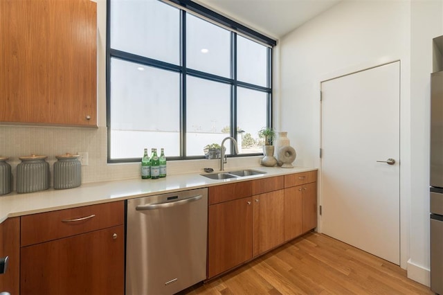 kitchen with backsplash, dishwasher, light wood-type flooring, and sink