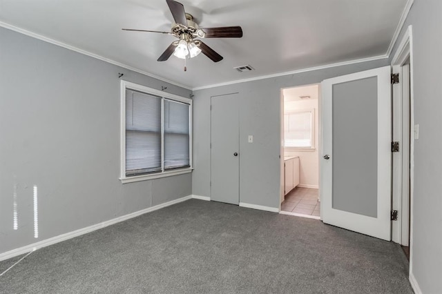 unfurnished bedroom featuring carpet, ensuite bathroom, crown molding, ceiling fan, and a closet