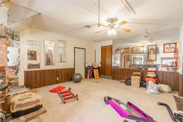 workout room with wooden walls, carpet floors, a textured ceiling, and ceiling fan