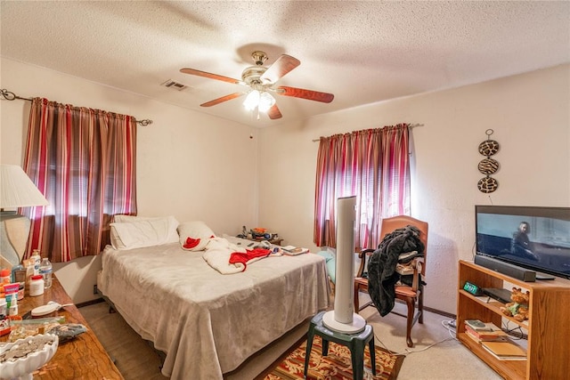 carpeted bedroom featuring ceiling fan and a textured ceiling