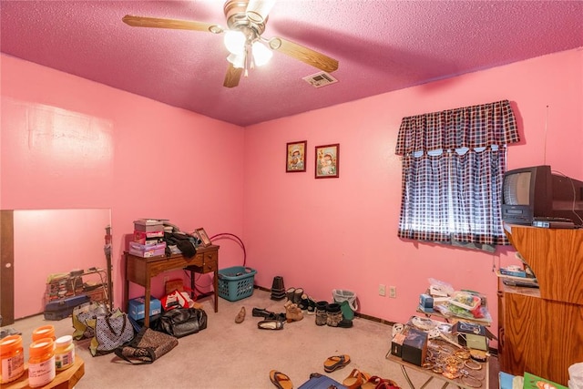 miscellaneous room featuring ceiling fan, carpet floors, and a textured ceiling