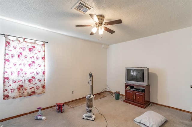 workout room featuring ceiling fan, light colored carpet, and a textured ceiling