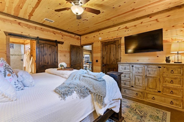 bedroom featuring wood walls, ceiling fan, a barn door, and wood ceiling