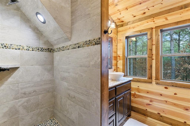 bathroom featuring wood walls, vanity, and vaulted ceiling