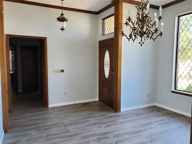 foyer featuring a chandelier, hardwood / wood-style floors, a wealth of natural light, and ornamental molding