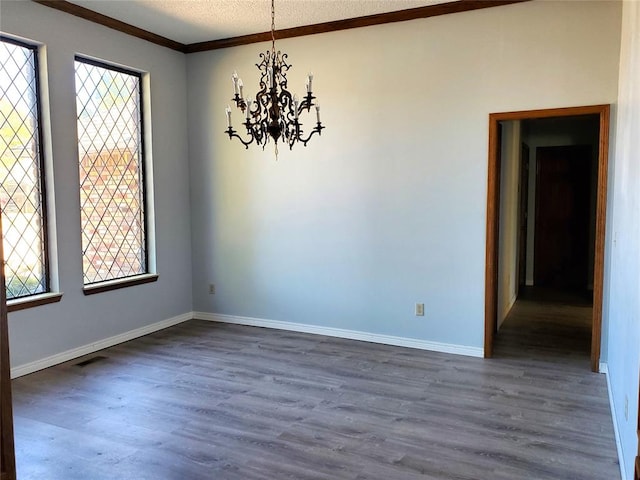 unfurnished room with a textured ceiling, ornamental molding, dark wood-type flooring, and a chandelier