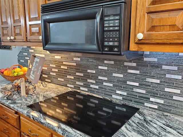 room details featuring dark stone counters, decorative backsplash, and black appliances