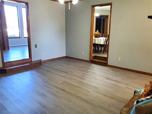 empty room with ceiling fan and light hardwood / wood-style flooring