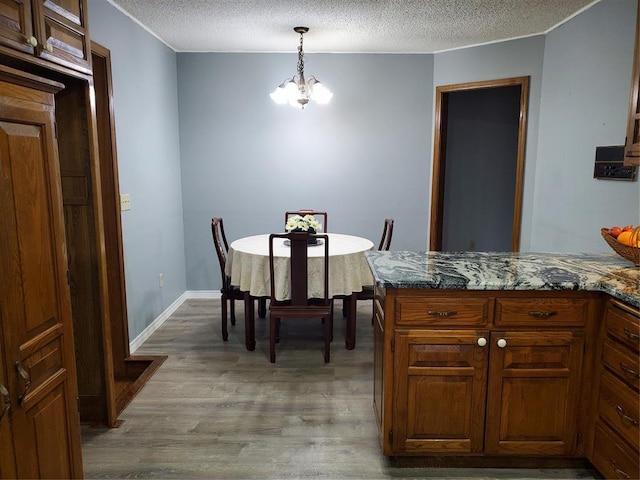 dining room featuring a chandelier, a textured ceiling, and light wood-type flooring