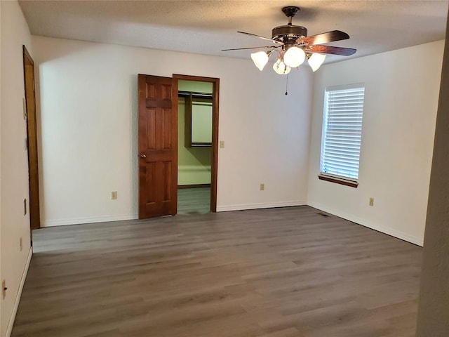 unfurnished room with a textured ceiling, ceiling fan, and dark wood-type flooring