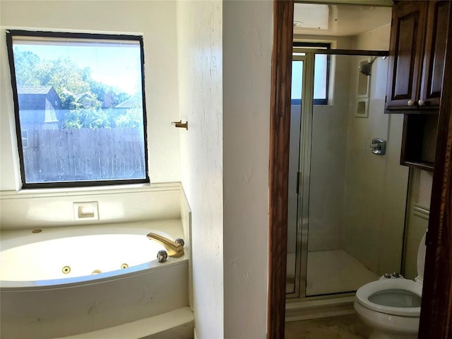 bathroom featuring plus walk in shower, a healthy amount of sunlight, and toilet