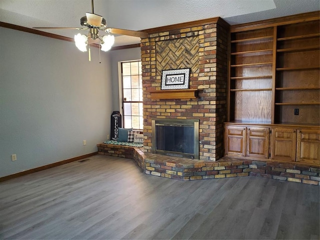 unfurnished living room featuring ceiling fan, wood-type flooring, a textured ceiling, and a brick fireplace