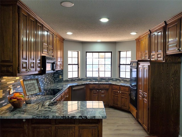 kitchen featuring backsplash, dark stone counters, black appliances, sink, and kitchen peninsula