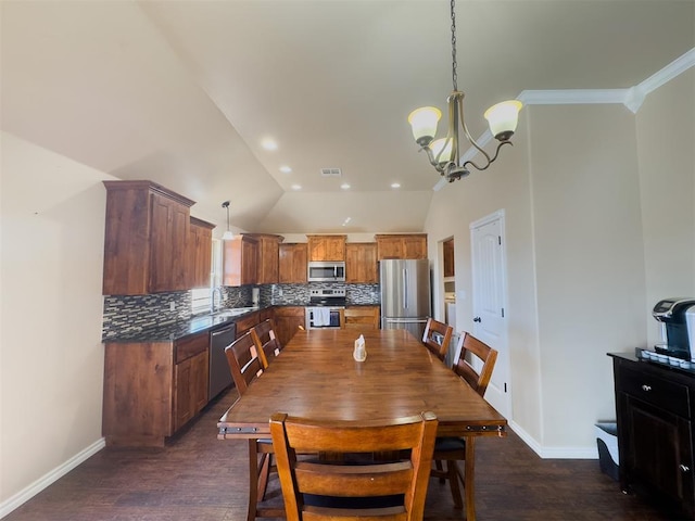 dining area featuring sink, vaulted ceiling, dark hardwood / wood-style floors, ornamental molding, and a notable chandelier