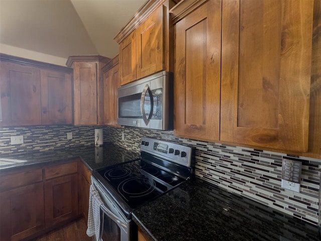 kitchen with decorative backsplash, appliances with stainless steel finishes, dark stone counters, vaulted ceiling, and dark hardwood / wood-style floors