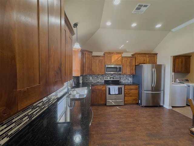 kitchen with stainless steel appliances, dark wood-type flooring, sink, decorative light fixtures, and washing machine and clothes dryer