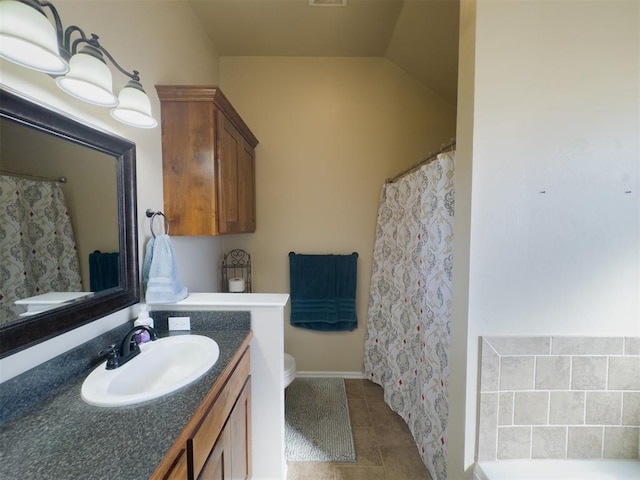 bathroom with toilet, vanity, tile patterned floors, and vaulted ceiling