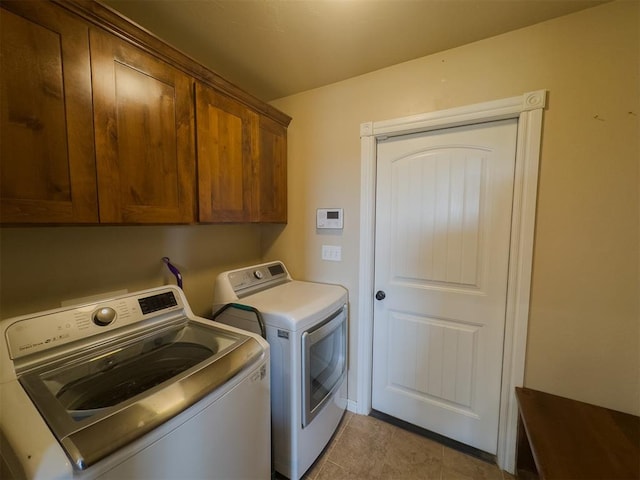 laundry room with cabinets, light tile patterned floors, and separate washer and dryer