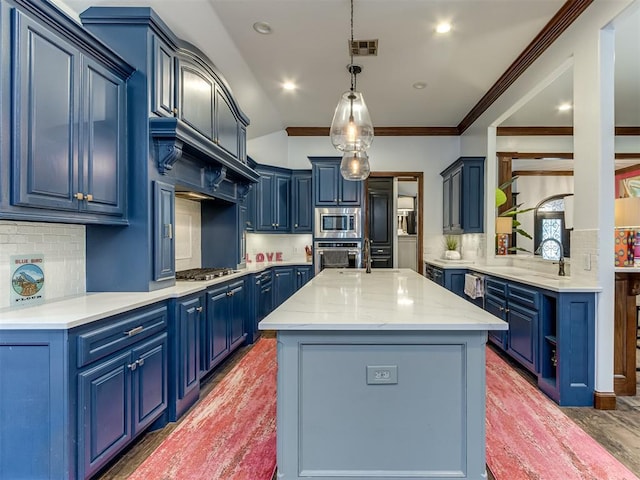 kitchen featuring blue cabinetry, pendant lighting, stainless steel appliances, and an island with sink