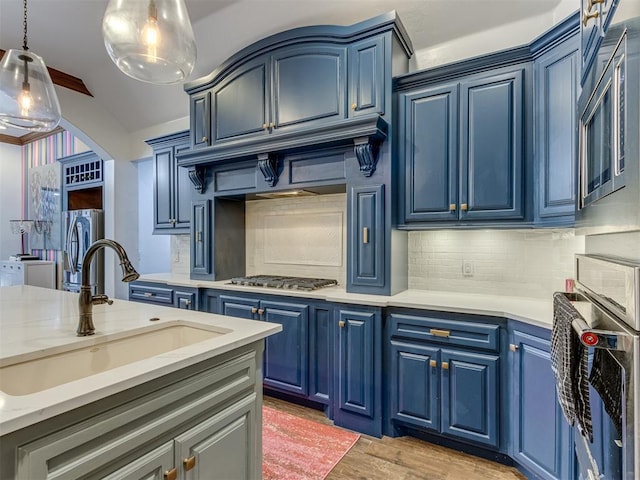 kitchen featuring light hardwood / wood-style floors, blue cabinets, hanging light fixtures, and sink