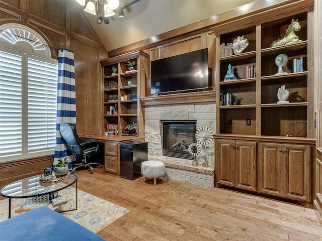 home office featuring lofted ceiling, wooden walls, ceiling fan, light wood-type flooring, and a fireplace