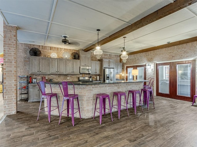 bar featuring brick wall, stainless steel appliances, ceiling fan, dark wood-type flooring, and hanging light fixtures